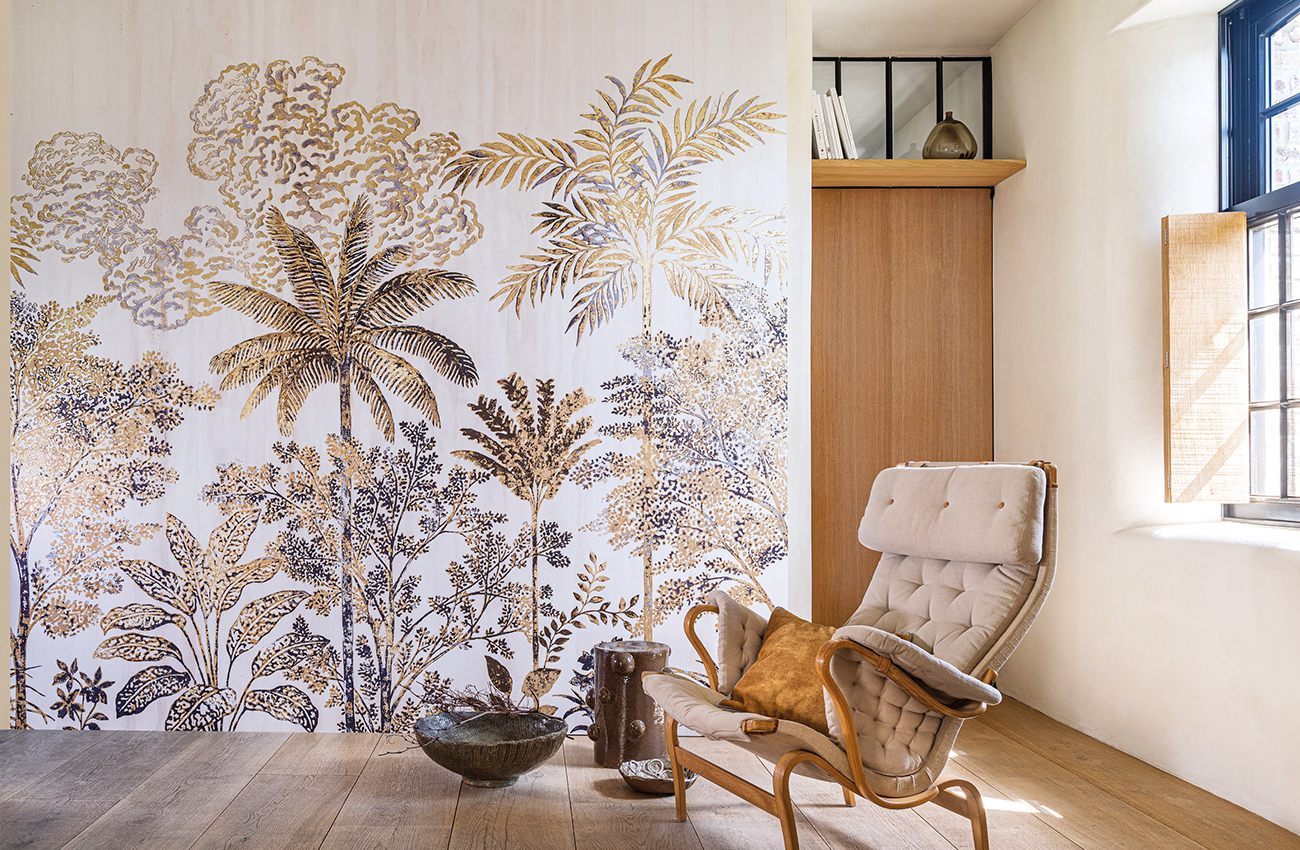 salon pièce à vivre intérieur avec fauteuil matelassé marron, papier peint floral exotique avec sol en parquet chêne